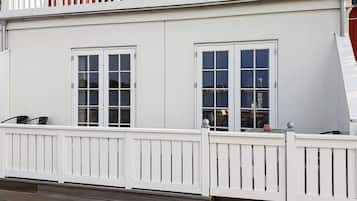 Ein zweistöckiges Gebäude mit weißen Außenwänden, einem Balkon mit roten Geländern und einem weißen Zierzaun.