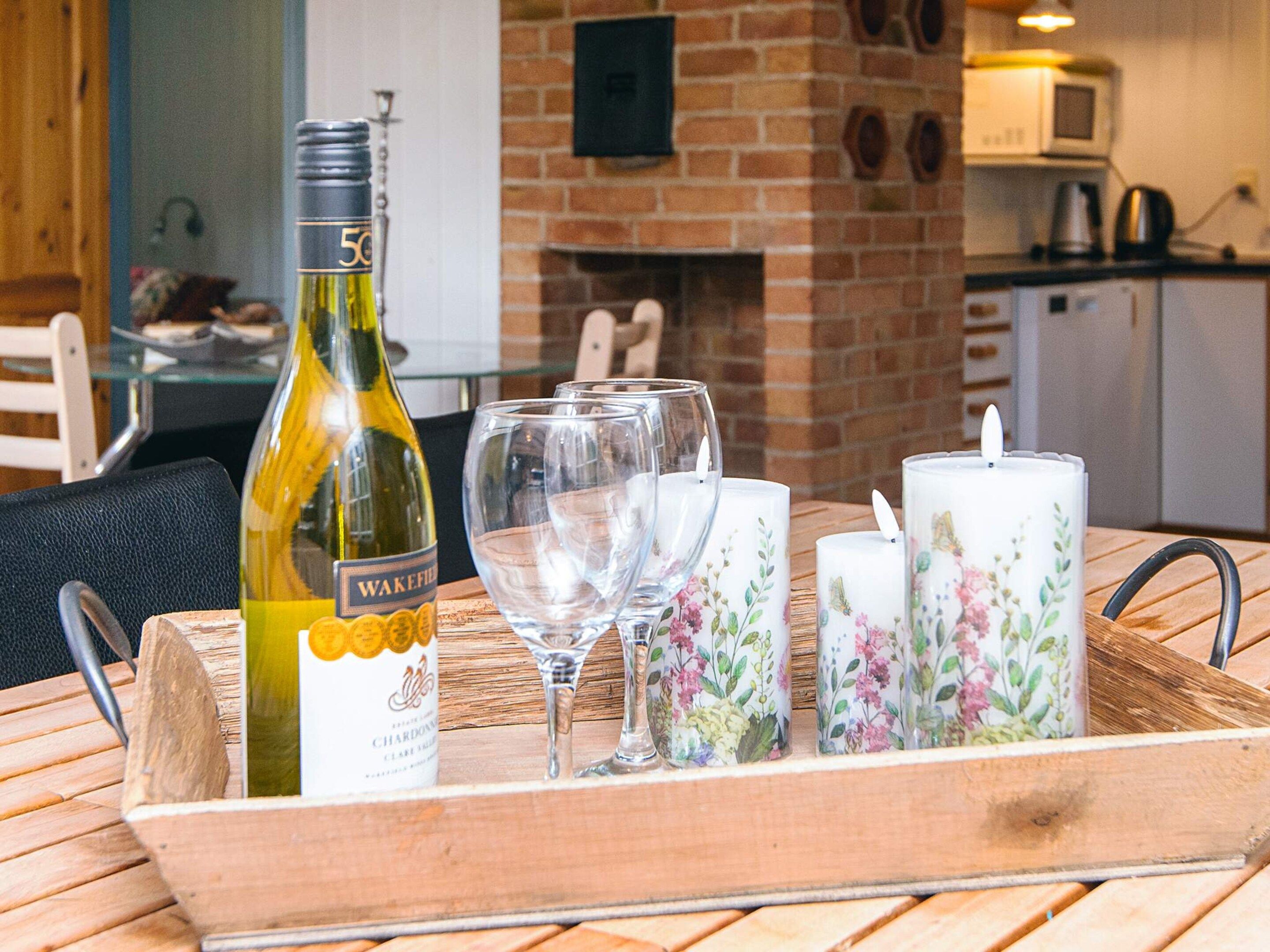 A tray with a bottle of wine, empty wine glasses, and decorative candles on a wooden table.