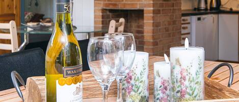 A tray with a bottle of wine, empty wine glasses, and decorative candles on a wooden table.