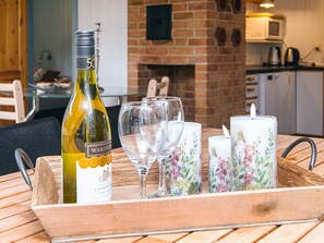 A tray with a bottle of wine, empty wine glasses, and decorative candles on a wooden table.