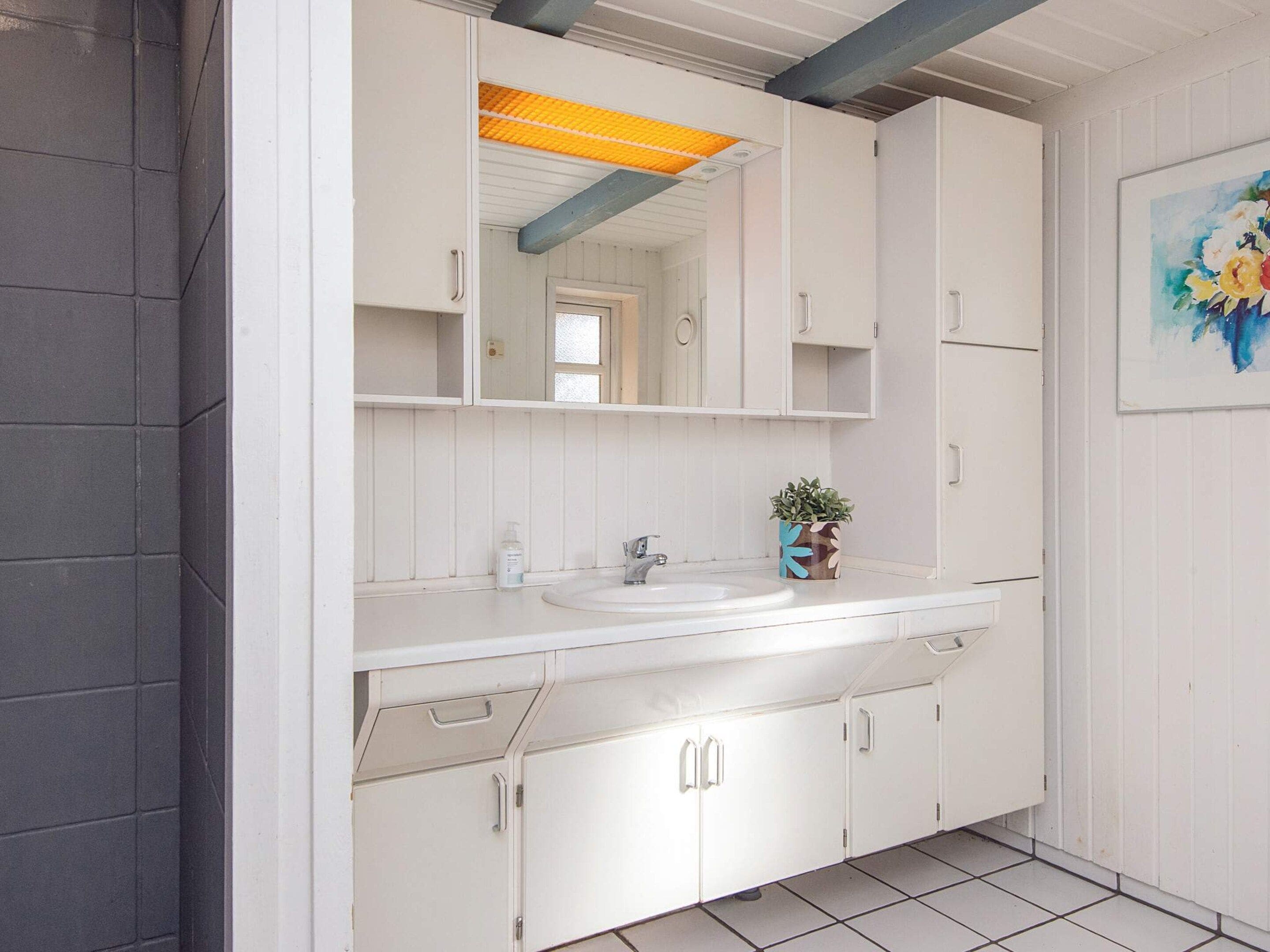 A bathroom with white cabinets, a sink, and a mirror.