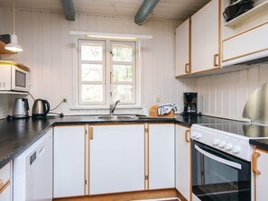 Eine Küche mit weißen Schränken, einer schwarzen Arbeitsplatte, einem Fenster, einer Mikrowelle, einer Kaffeemaschine und einem Backofen.