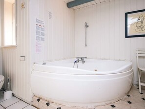 A bathroom with a large white bathtub, a shower, and a toilet. There are warning signs on the wall and a framed picture on the wall. - 14 Person Holiday Home in Ulfborg (Ulfborg)