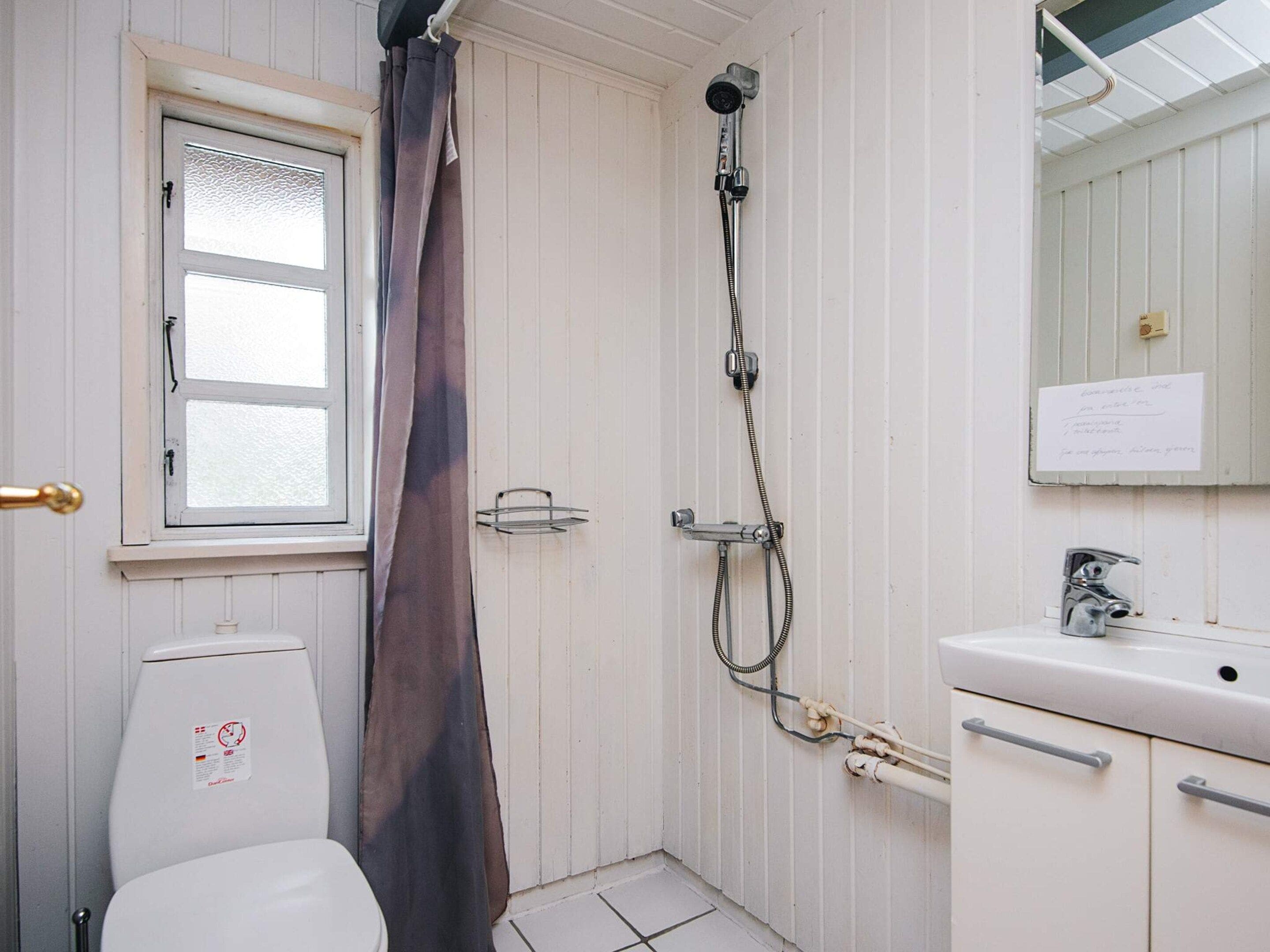 A small bathroom with a toilet, a shower, and a sink.