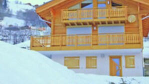 A two-story wooden chalet with balconies, set against a snowy mountain backdrop. - Lavish Holiday Home in Heremence With Balcony (Heremence)