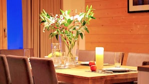 A dining area with a wooden table, chairs, a vase with flowers, a candle, and a glass of water. - Lavish Holiday Home in Heremence With Balcony (Heremence)