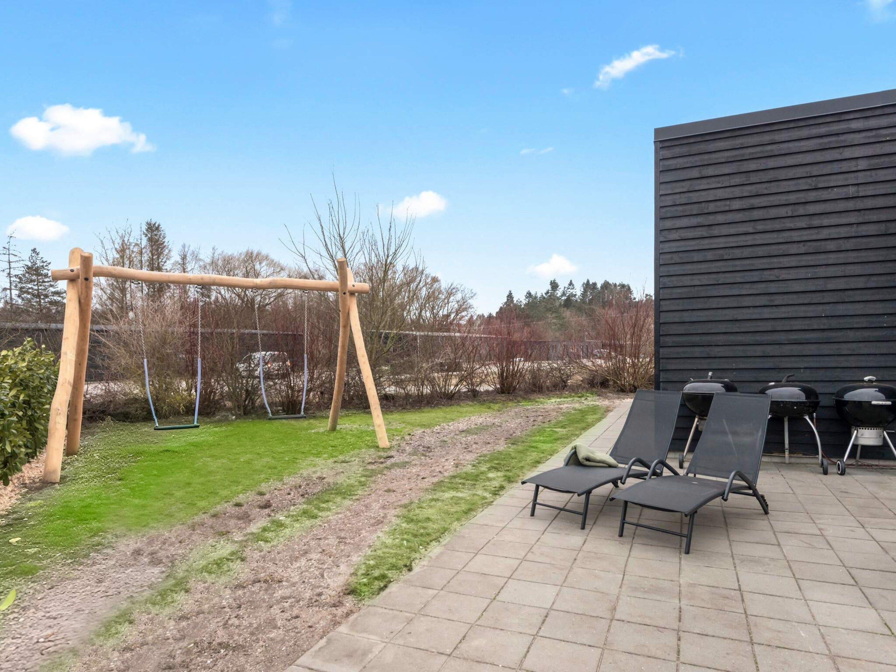 Ein Patio mit Schaukel, Liegestühlen und Grill.