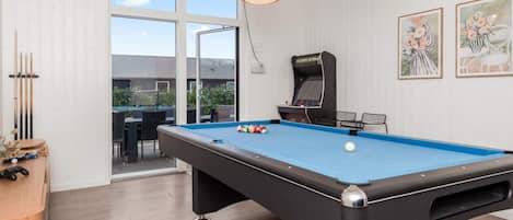 A pool table with balls, a pool cue rack, and a table tennis table.