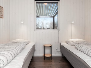 A room with two beds, a small table, and a window with a view of trees. - Holiday Home in Glesborg (Glesborg)
