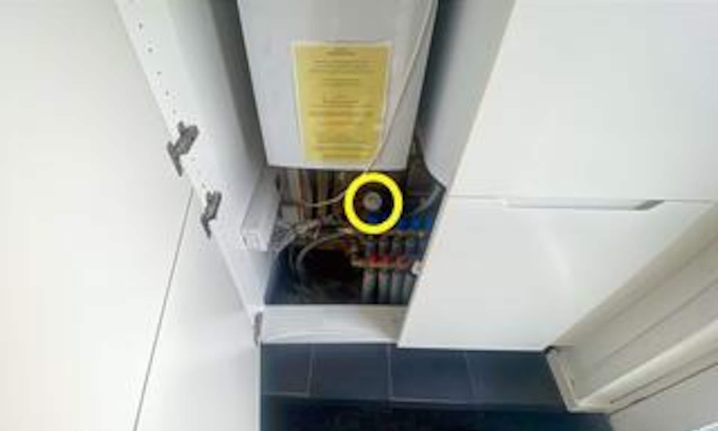 An open refrigerator with a yellow warning label, a visible power cord, and a control panel.