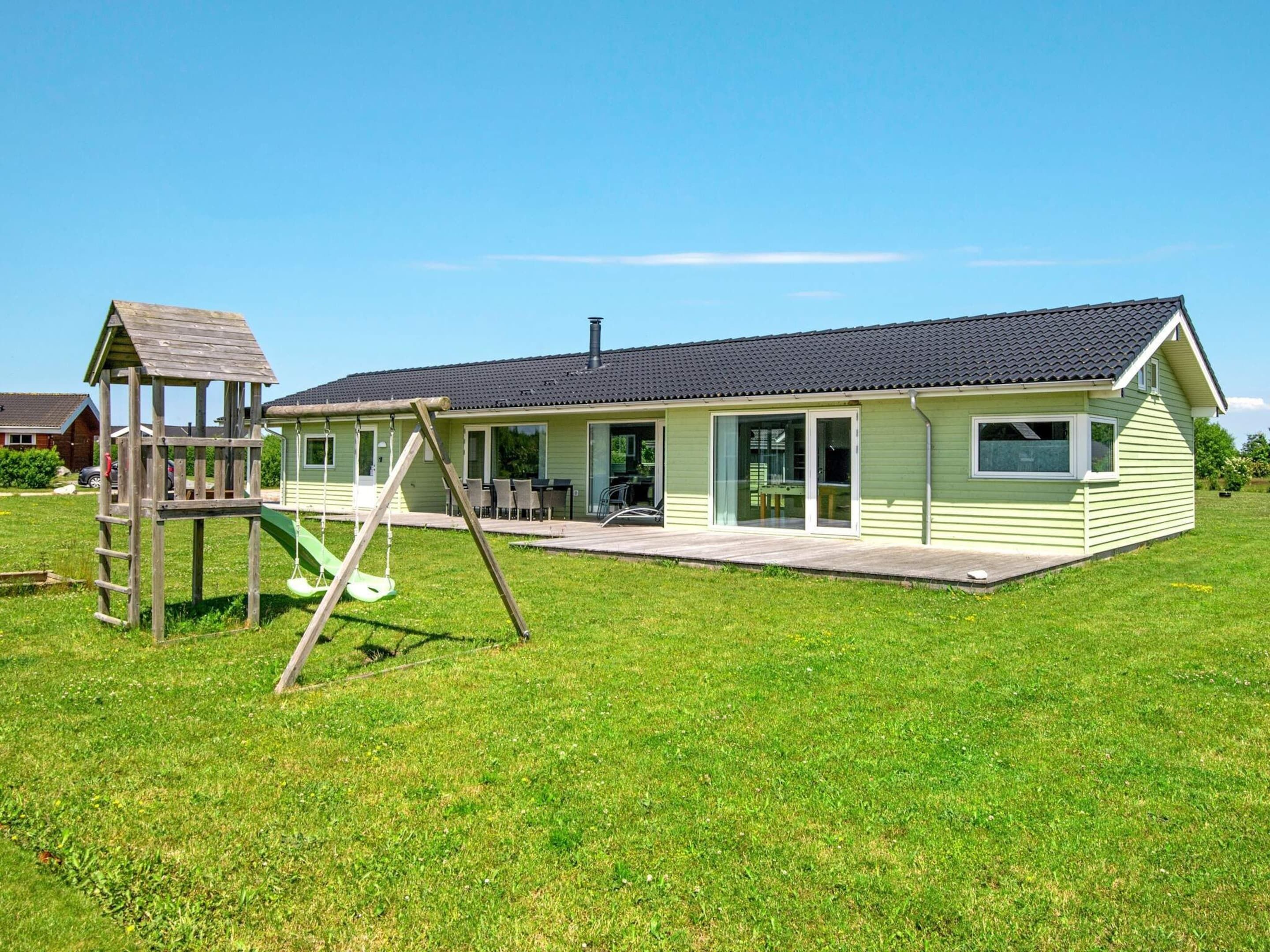 A single-story house with a patio, a swing set, and a small playhouse.