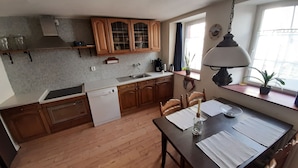 A kitchen with wooden cabinets, a dishwasher, a sink, and a dining table with chairs. - Beautiful Holiday Home With Terrace (Nattenheim)