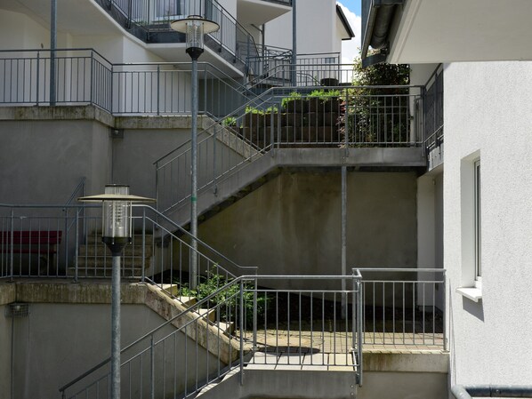 A multi-level residential building with external staircases, metal railings, and a light fixture.
