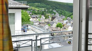 A residential area with houses, a balcony, and a view of a forested hill. - Grosse Ferienwohnung in Willingen mit Balkon (Willingen)