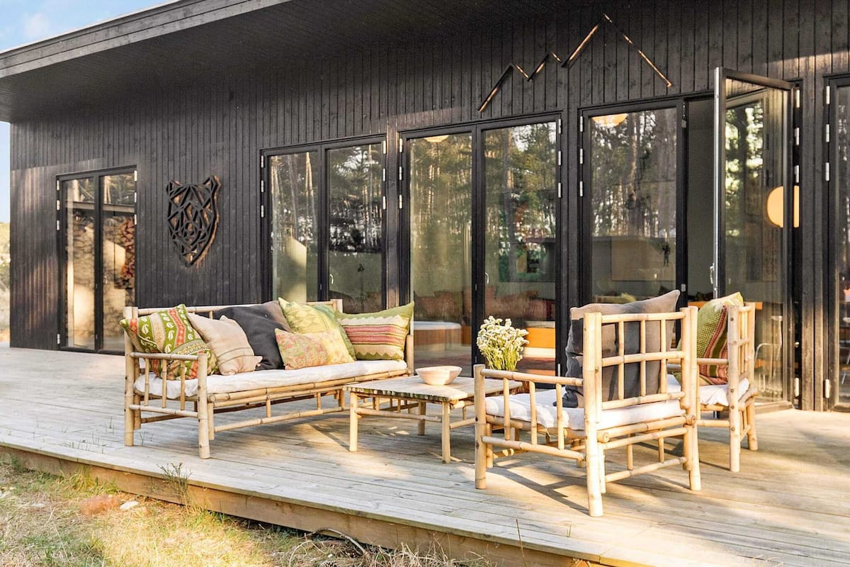 A modern outdoor seating area with a wooden deck, a sofa, and two chairs.