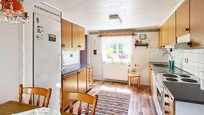 A compact kitchen with wooden cabinets, a stove, and a dining area with a table and chairs. - 7 Person Holiday Home in Almedboda (Älmeboda)