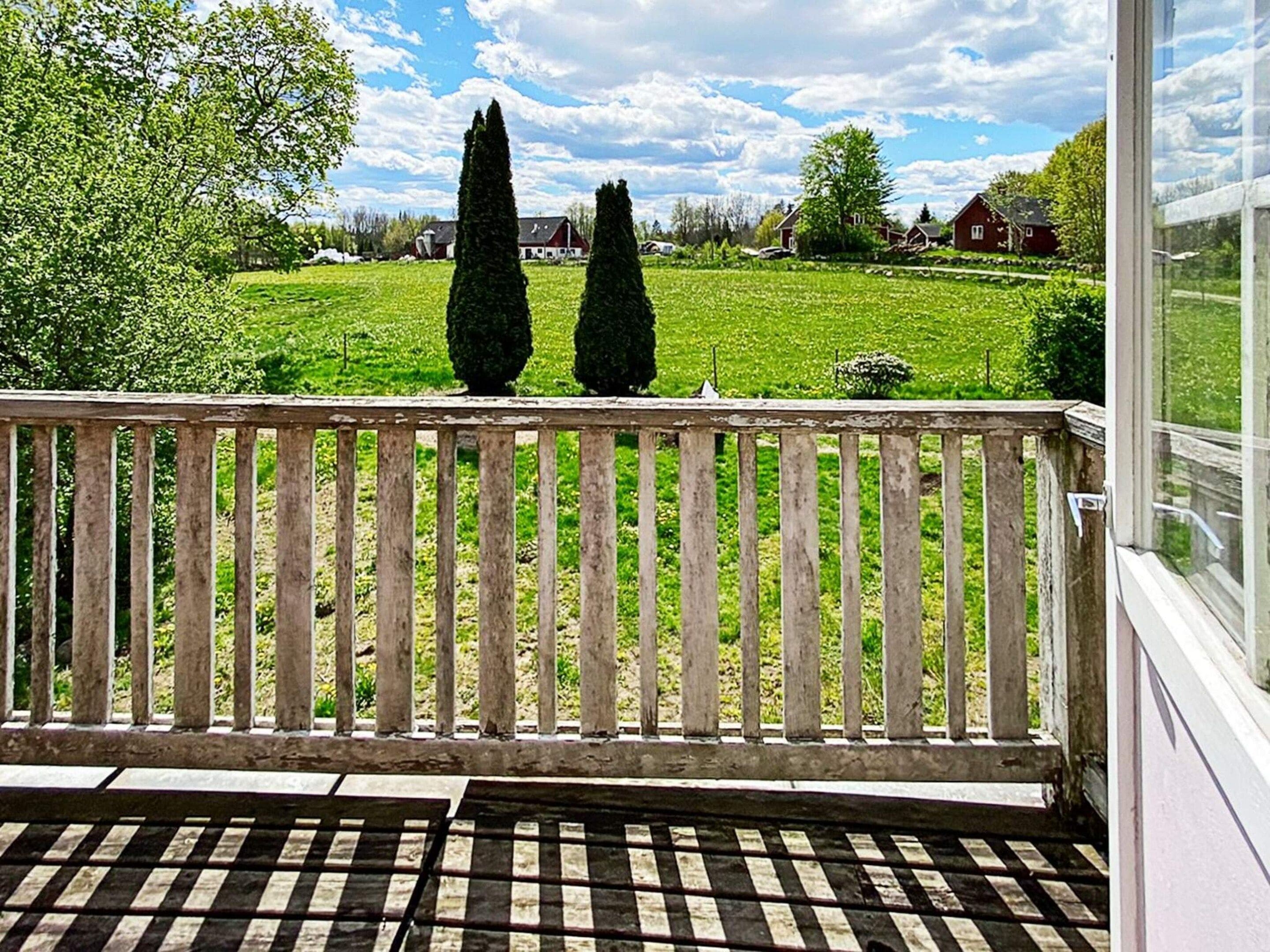 A balcony with a view of a green field and houses in the distance.