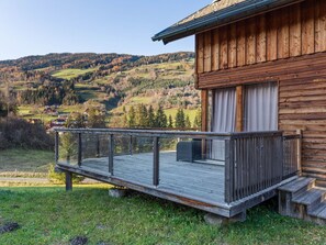 Eine Holzblockhütte mit einer Terrasse und Blick auf ein Tal.