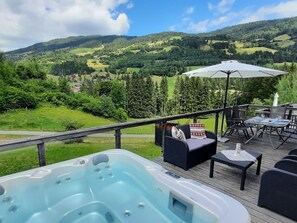 A hot tub on a deck with outdoor furniture and a scenic view of a valley. - Chalet in St. Georgen ob Murau (Sankt Georgen am Kreischberg)