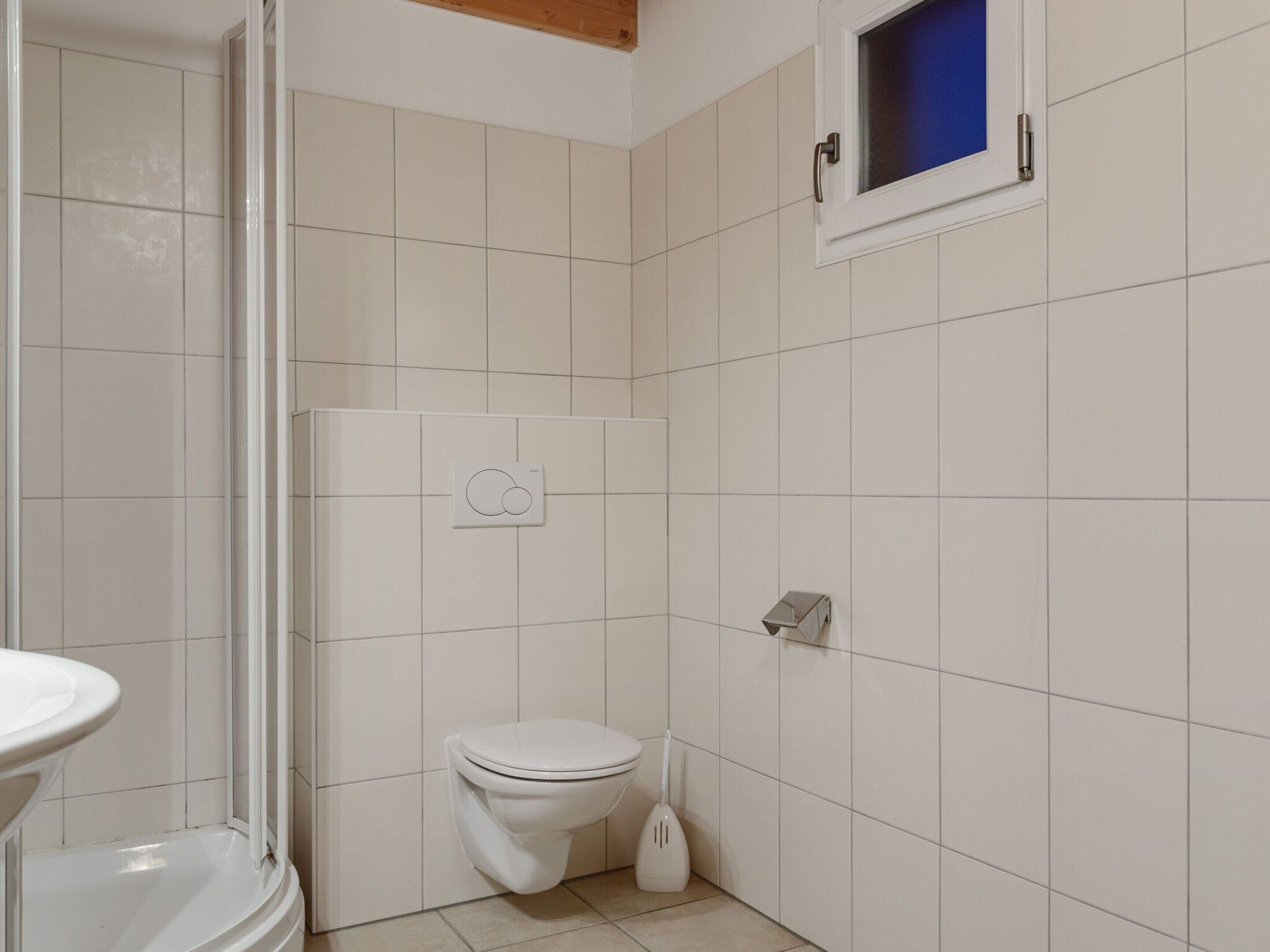A bathroom with a toilet, a bidet, and a window with a blue view.