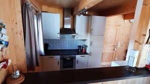Une cuisine de taille réduite avec des meubles en bois, un plan de travail noir et une cuisinière.
