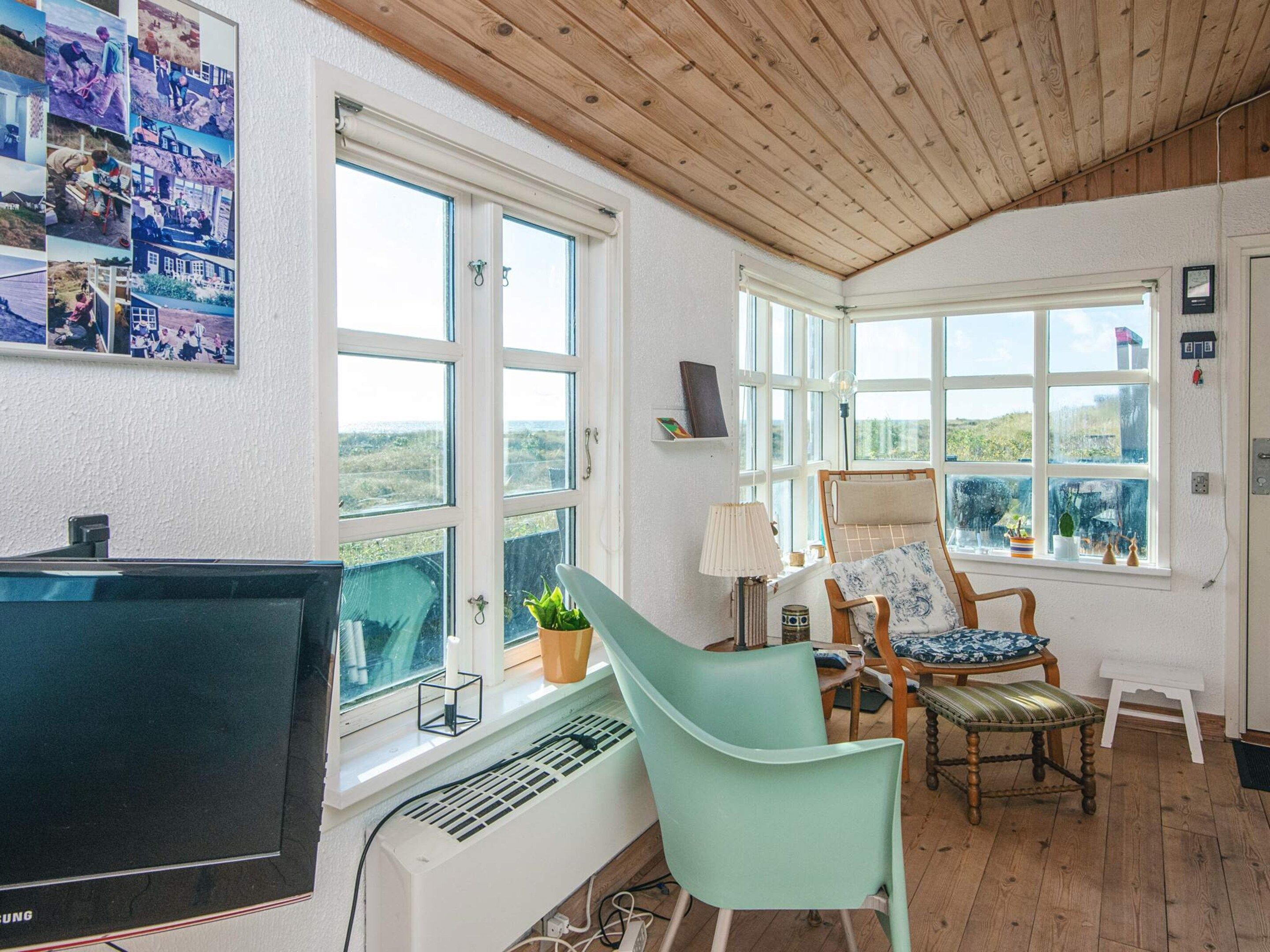 A room with a large window, a desk with a computer, a chair, and a radiator.