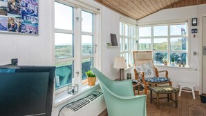A room with a large window, a desk with a computer, a chair, and a radiator.