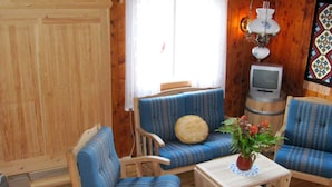 Um quarto acolhedor em estilo cabana, com paredes de madeira, um sofá azul listrado, uma mesa de madeira e uma televisão.