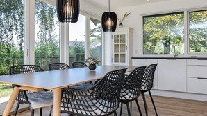 A modern kitchen with a large dining table, black chairs, and pendant lights. - Holiday Home in Idestrup (Idestrup)