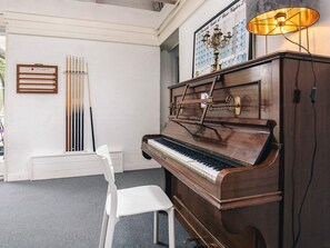 A piano with a wall-mounted display of beer styles, a white chair, and a chandelier. - Holiday Home in VÃ¦ggerlÃ¸se (Vaeggerlose)