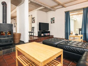 A cozy living room with a fireplace, a sofa, a television, and a small table.