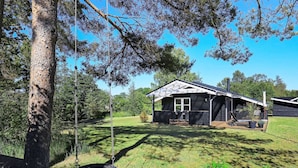 Ein Haus mit Veranda, Schaukel und Rasenfläche.