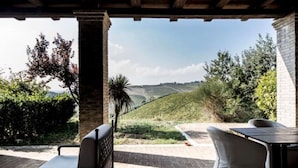 An outdoor patio with a view of rolling hills, a table, and a chair. - Apartment in Marche Near Sibillini Park (Ripatransone)