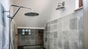 A modern shower area with a rain showerhead and a handheld showerhead, tiled walls, and a visible window in the background. - Apartment in Marche Near Sibillini Park (Ripatransone)