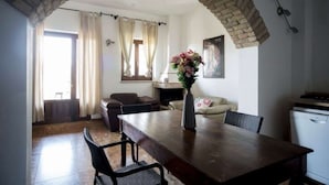 A dining area with a brick arch, a wooden table, and chairs. There is a vase with flowers on the table. - Apartment in Marche Near Sibillini Park (Ripatransone)