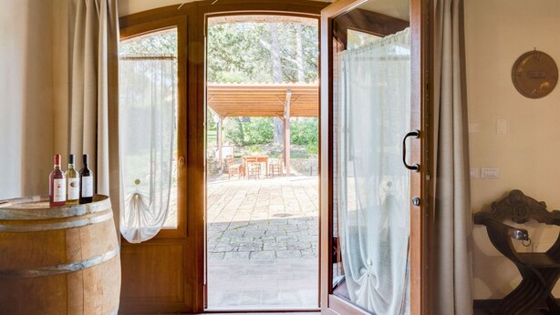 Une pièce avec une porte en bois donnant sur un patio extérieur, un tonneau en bois et une table avec des chaises.