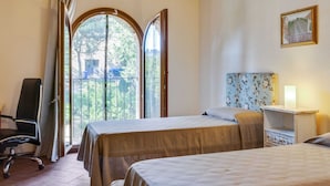 Une chambre avec deux lits, une chaise, une table de chevet et une fenêtre avec des rideaux.