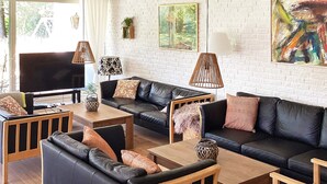 A modern living room with leather sofas, wooden tables, and a white brick wall. - 12 Person Holiday Home in Vaeggerlose (Vaeggerlose)