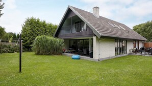A modern two-story house with a large balcony, a covered patio, and a well-maintained lawn. - 12 Person Holiday Home in Vaeggerlose (Vaeggerlose)