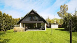 A modern two-story house with a large front lawn, a dining area, and a visible satellite dish. - 12 Person Holiday Home in Vaeggerlose (Vaeggerlose)