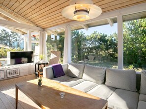 A modern living room with a wooden ceiling, large windows, a sofa, a TV, and a wooden table. - 10 Person Holiday Home in Slettestrand Fjerritslev (Fjerritslev)