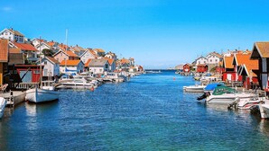 Un puerto con barcos amarrados a lo largo del agua, rodeado de edificios coloridos con fachadas rojas y blancas.