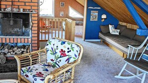 Acogedor dormitorio en ático con chimenea de ladrillo, techo de madera y una pared azul de acento.