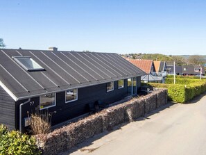 A modern house with a sloped roof, a visible chimney, and a paved driveway.