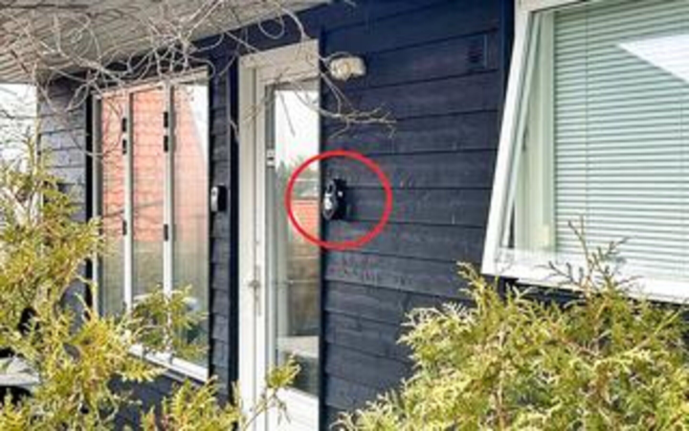 A house with a dark exterior, a visible door, and a window with blinds.