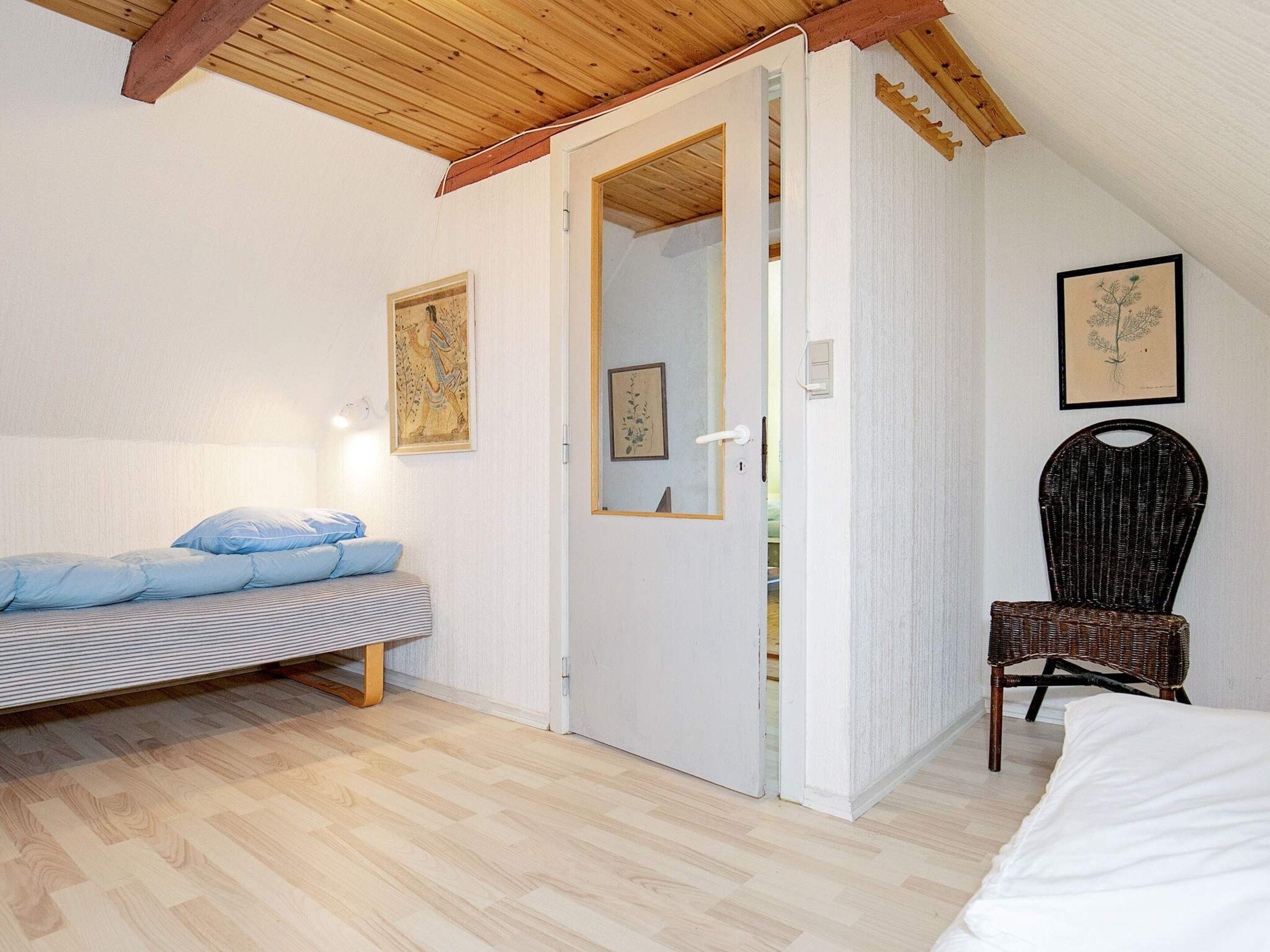 Een slaapkamer met een bed, een stoel en een deur naar een andere kamer.