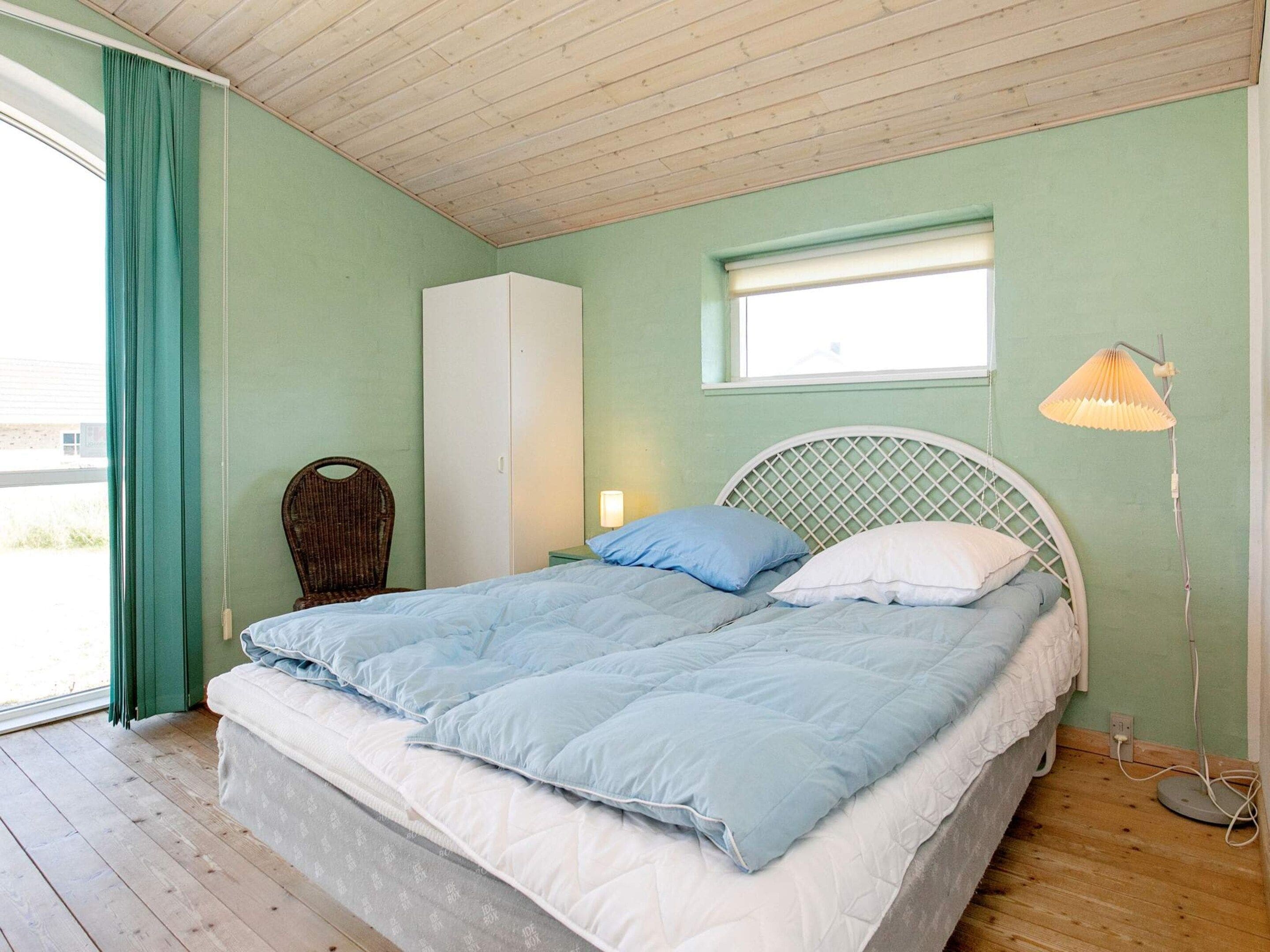 Una habitación con cama, armario, ventana y lámpara.