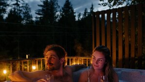 Two people sitting in a hot tub outdoors at night. - Cozy and Modern Getaway (Revelstoke)