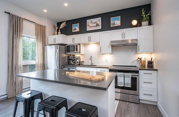 A modern kitchen with white cabinets, stainless steel appliances, and a central island.