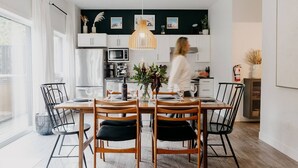 A modern kitchen with white cabinets, a central island, and a hanging pendant light. - Cozy and Modern Getaway (Revelstoke)